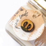 Vela promocional ecólogica en cristal con aroma y semillas de pino color caqui tercera vista