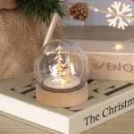 Bola iluminada con diseño navideño en el interior y base de madera vista de ambiente