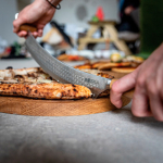 Cuchillo para pizza y queso de doble agarre de acero inoxidable Boska color plateado vista de ambiente