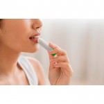 Bálsamo labial vegano con aroma de vainilla y envase transparente vista bodegón