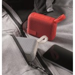 Pequeño altavoz inalámbrico con asa a juego para transporte color rojo vista bodegón